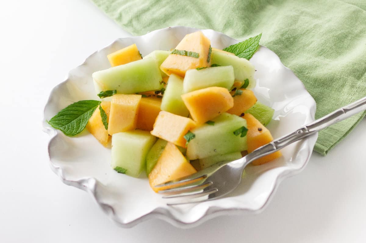 white ruffle edged salad bowl with melon salad with mint.