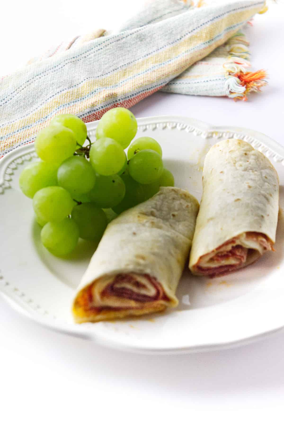 Monte Cristo Roll Ups on a plate of green grapes.