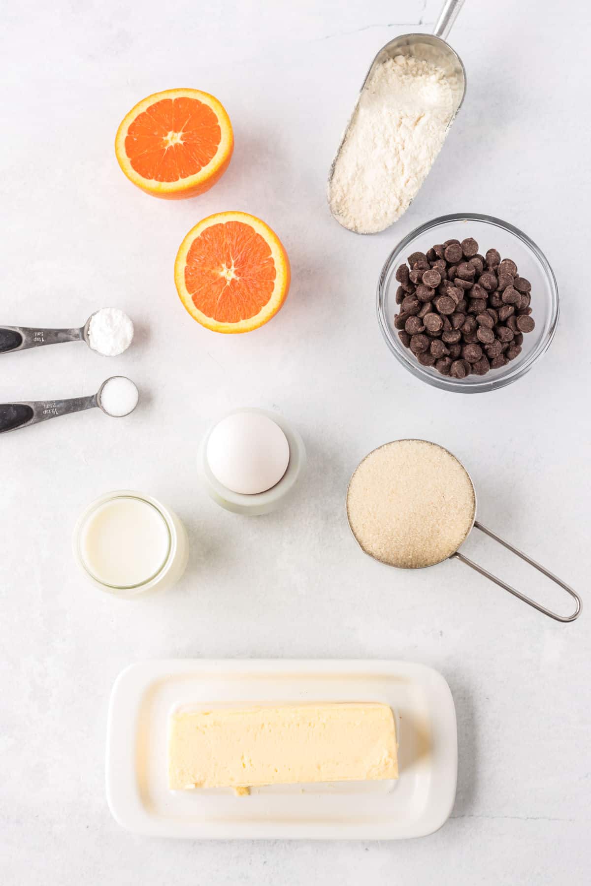 ingredients for orange breakfast muffins, chocolate chips, sugar, flour, milk, egg, oranges, butter
