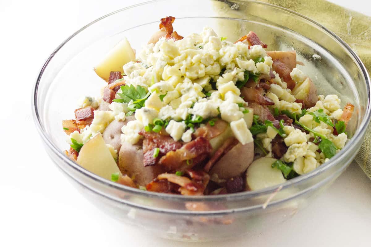 clear glass bowl with red skinned potatoes, bacon, and blue cheese.
