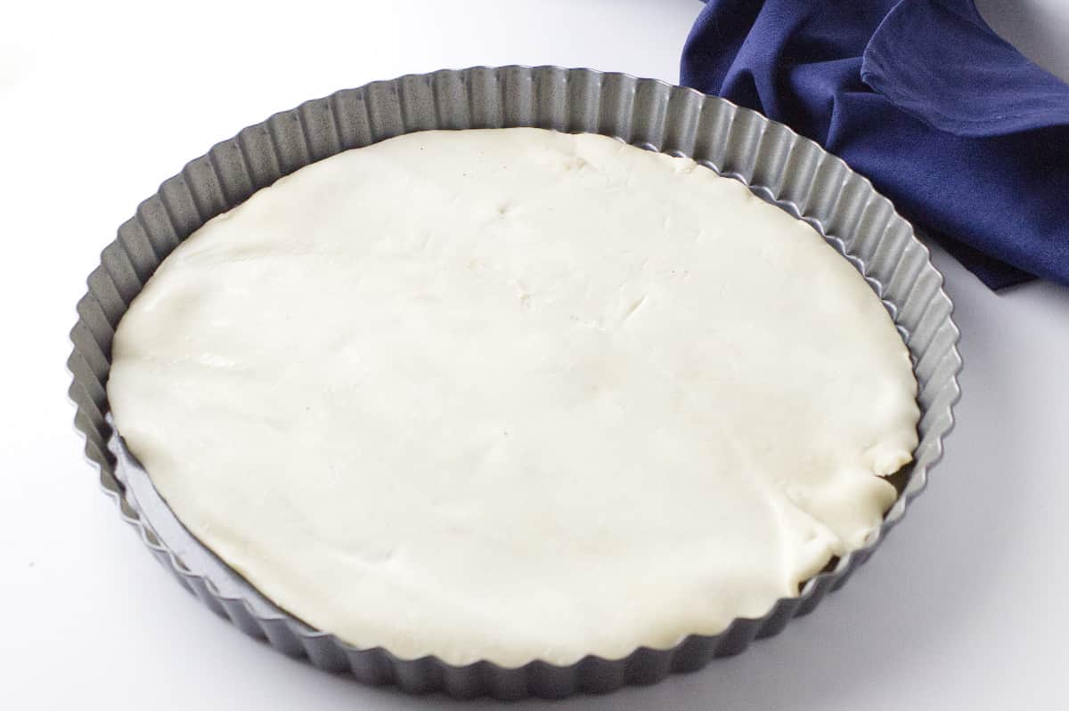 tart pan with an uncooked pie crust covering the bottom