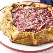 red rimmed white cake plate with baked rhubarb gallette sprinkled with large grain sugar crystals