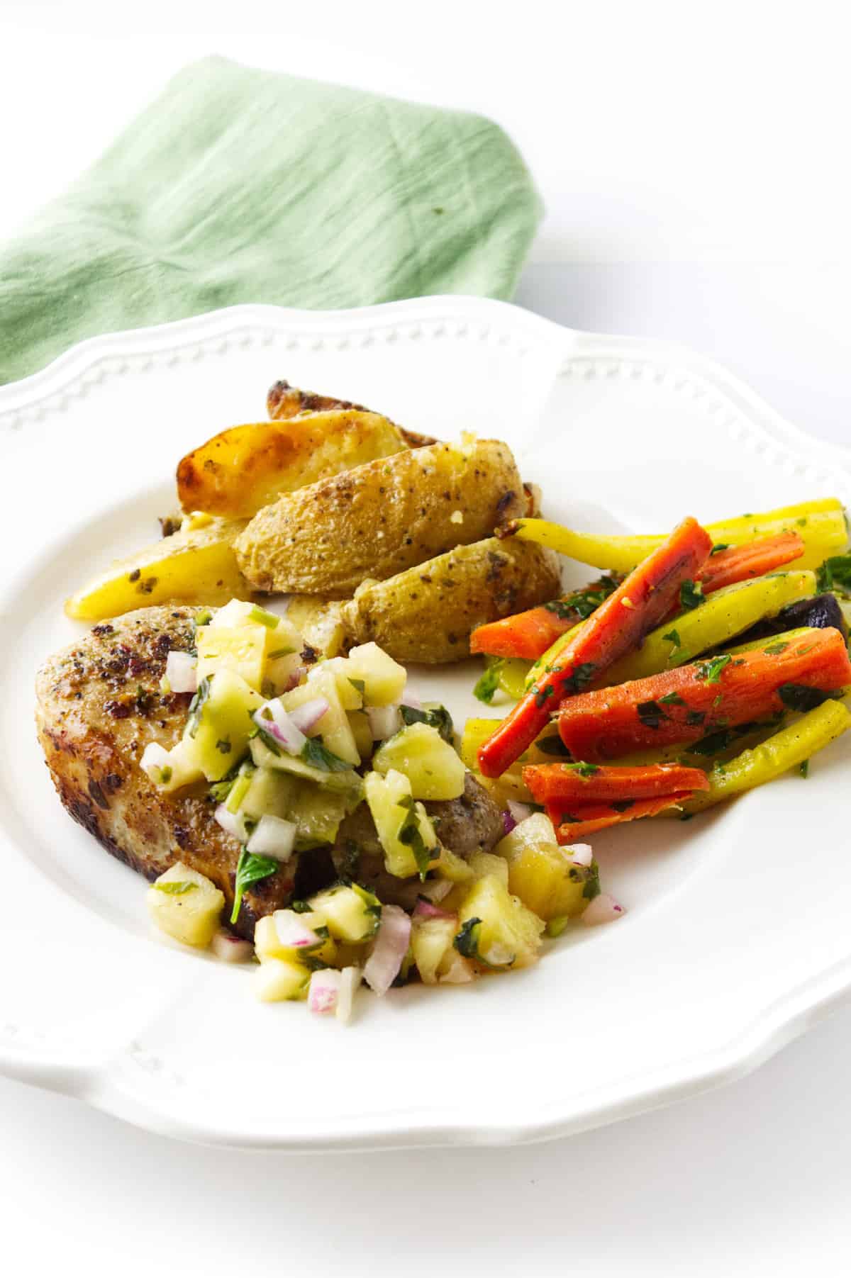 plate with grilled porkchop, pineapple salsa, roasted carrots, roasted potatoes.