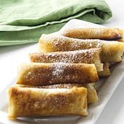 rectangle serving platter full of banana lumpia sprinkled with powdered sugar
