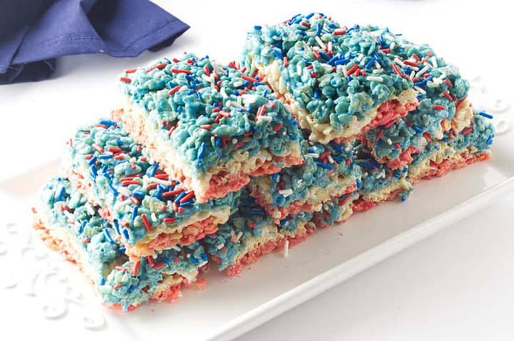 red white and blue layered Fourth of July rice crispy treats on a white platter.