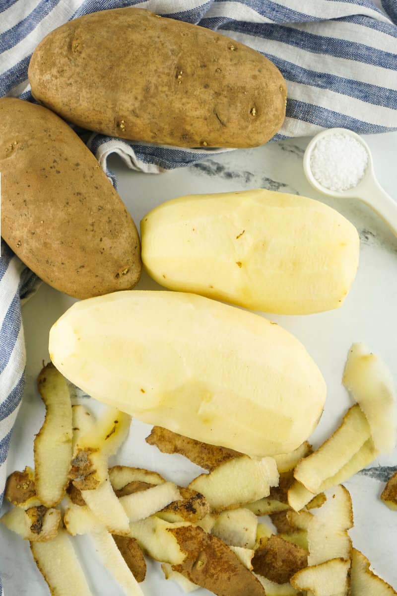 peeled potatoes with skins on counter.