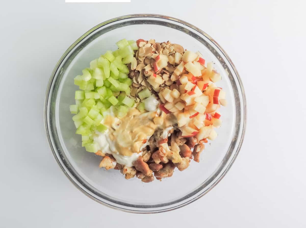 clear glass bowl with chicken, celery, apple and mayonnaise.