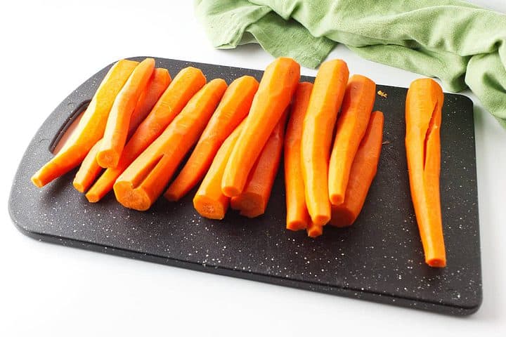 peeled carrots on a black cutting board.