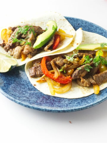 steak and rainbow bell peppers with avocado and cilantro on flour tortillas.