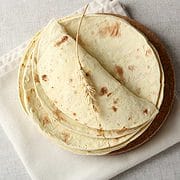 Stack of homemade whole wheat flour tortilla on napkin.