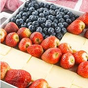 corner shot of a tray of blueberries, strawberries, and slices of white cheddar cheese
