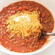 bowl of chili without beans topped with shredded cheddar cheese.