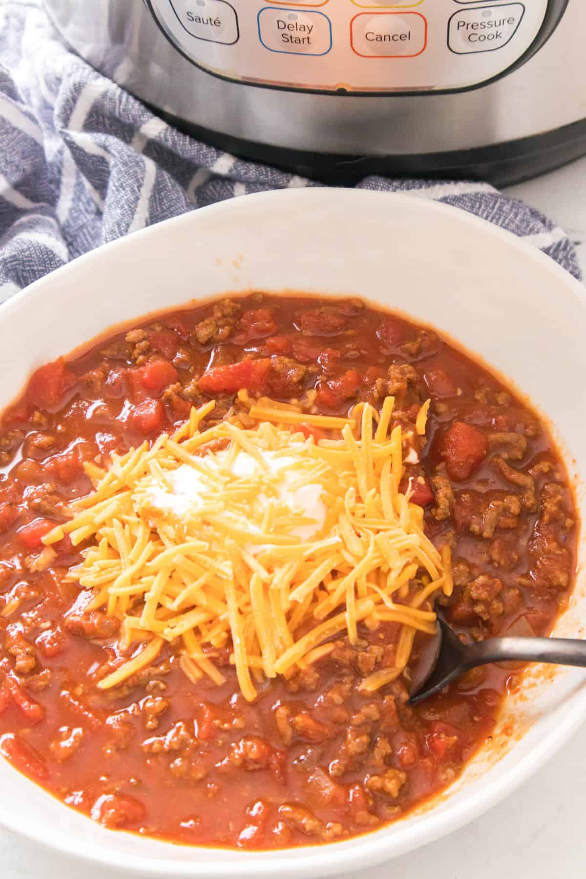 bowl of chili without beans topped with shredded cheddar cheese.