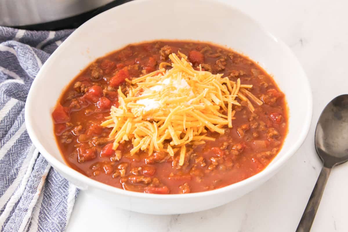 bowl of soup topped with shredded cheddar cheese.