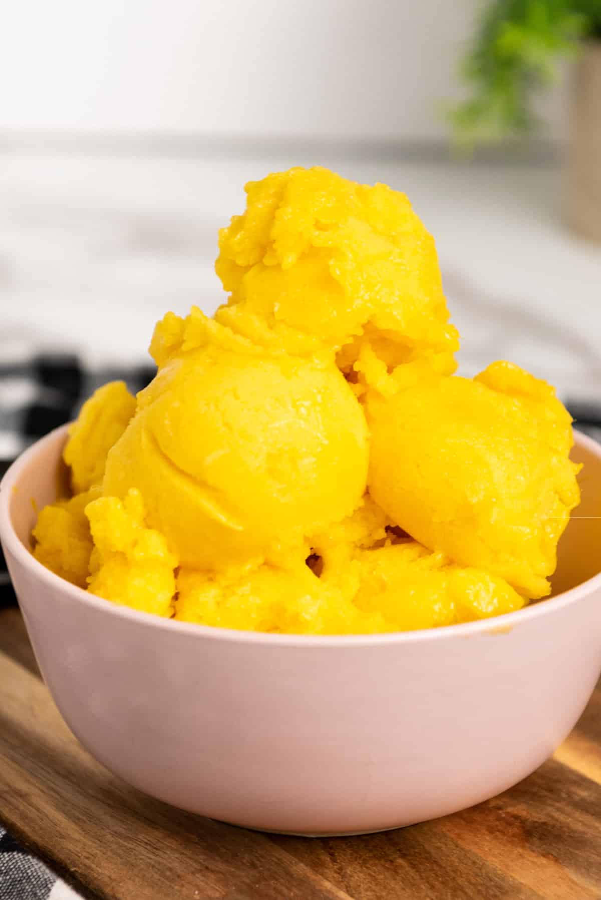 mango sorbet heaped up in scoops in a white bowl.