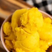 close up of scoops of mango sorbet in a bowl.