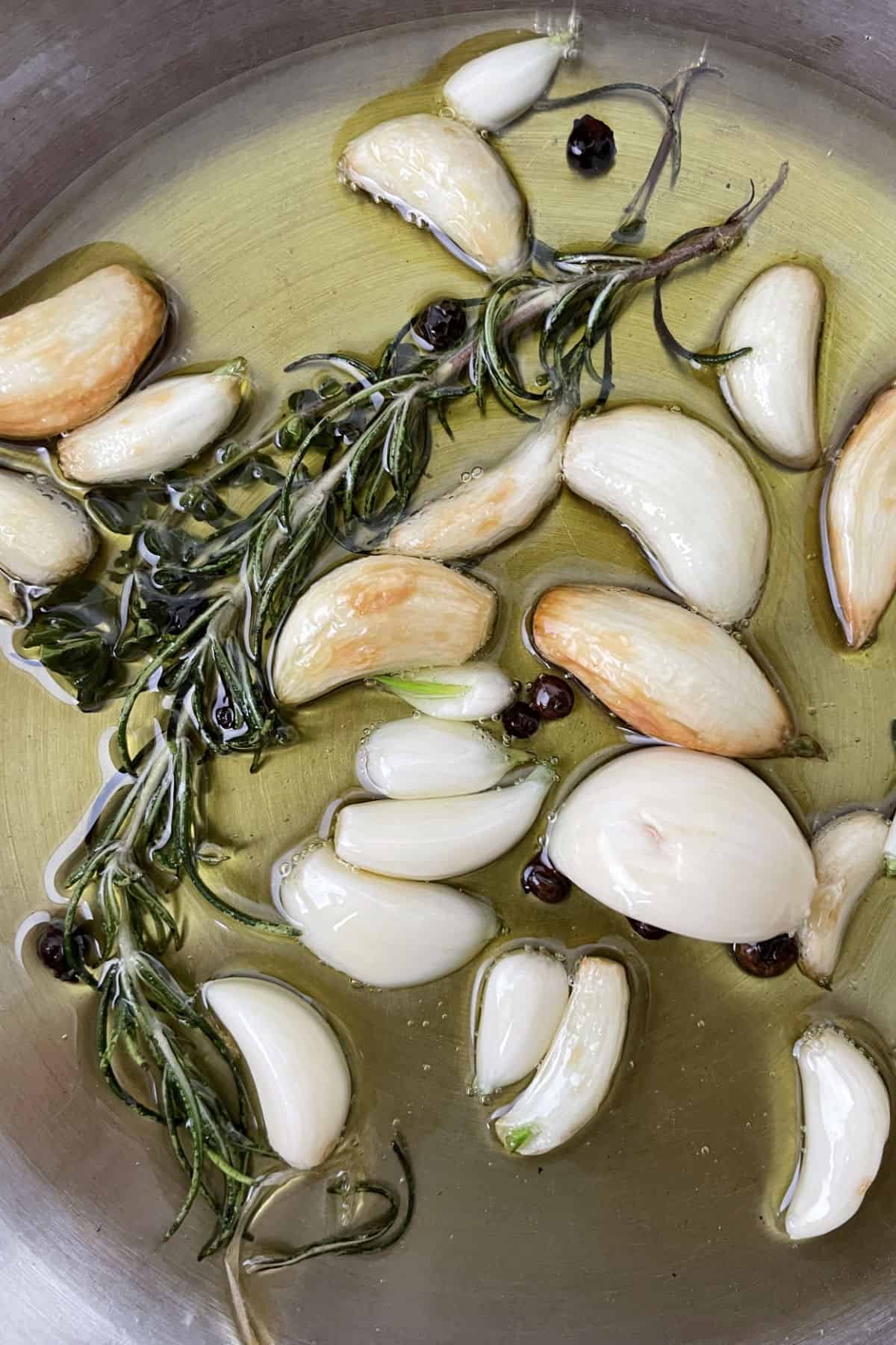 garlic and rosemary infusing warm olive oil in a skillet.