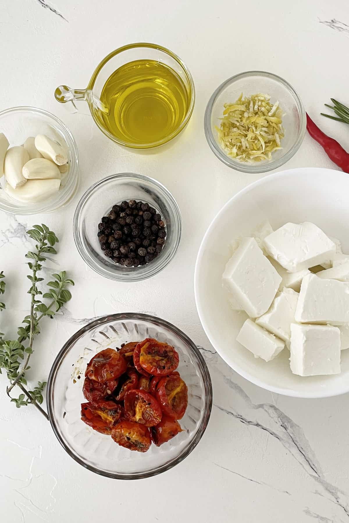 ingredients for marinating feta cheese with olive oil and herbs.