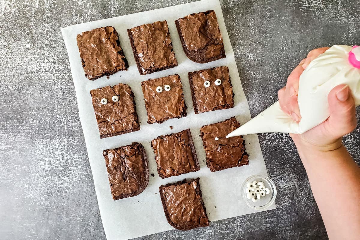 putting eyes on brownies with white frosting.