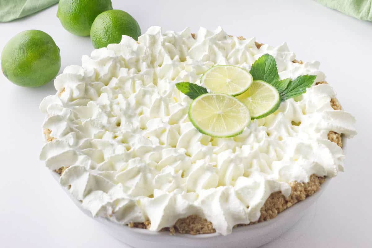 Whip cream rosettes and slices of lime decorate the no bake key lime pie.
