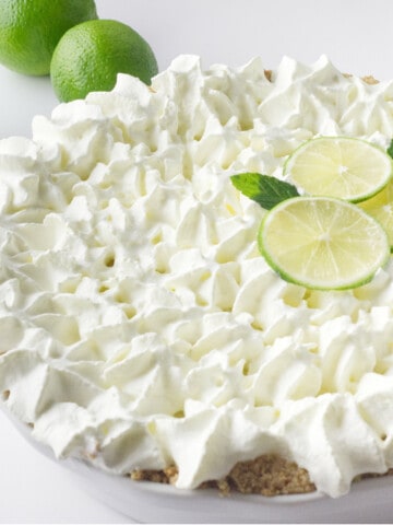 close up of pie with whip cream and lime slices.