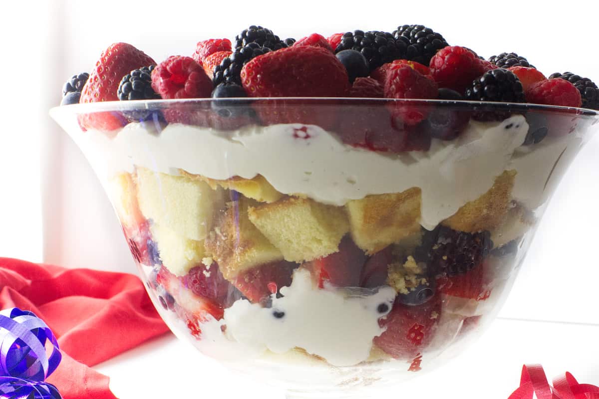 layers of cake, cheesecake, and berries in a side view of the berry trifle.
