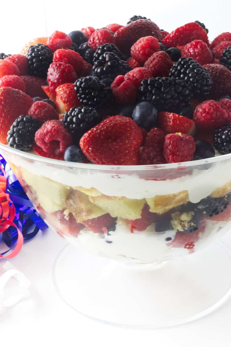 a large clear glass triffle bowl filled with a layered berry triffle.