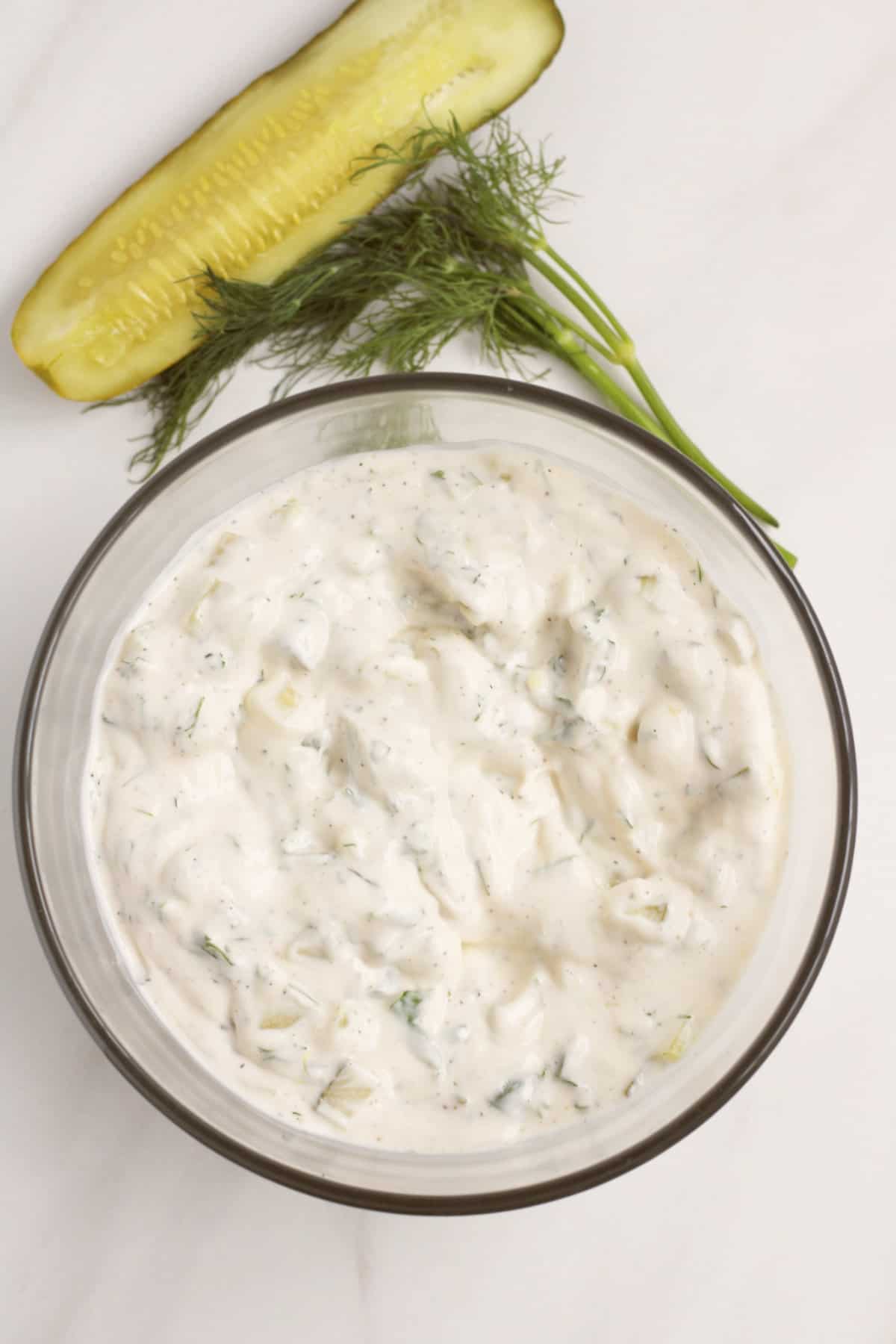 clear glass bowl of tartar sauce mixed with dill pickles and dill weed.