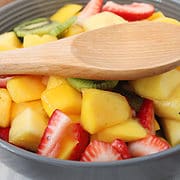 bowl of fruit salad with wooden spoon.