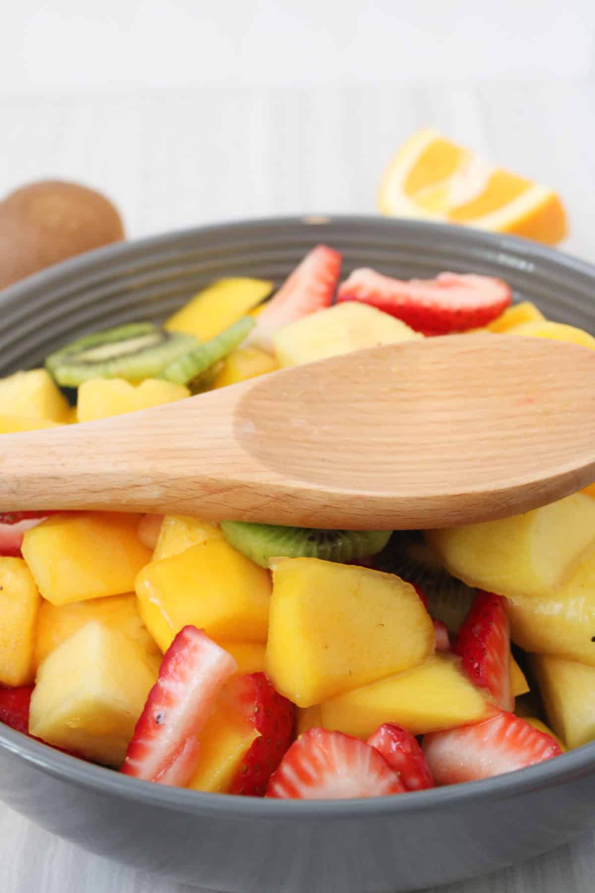 bowl of fruit salad with wooden spoon.