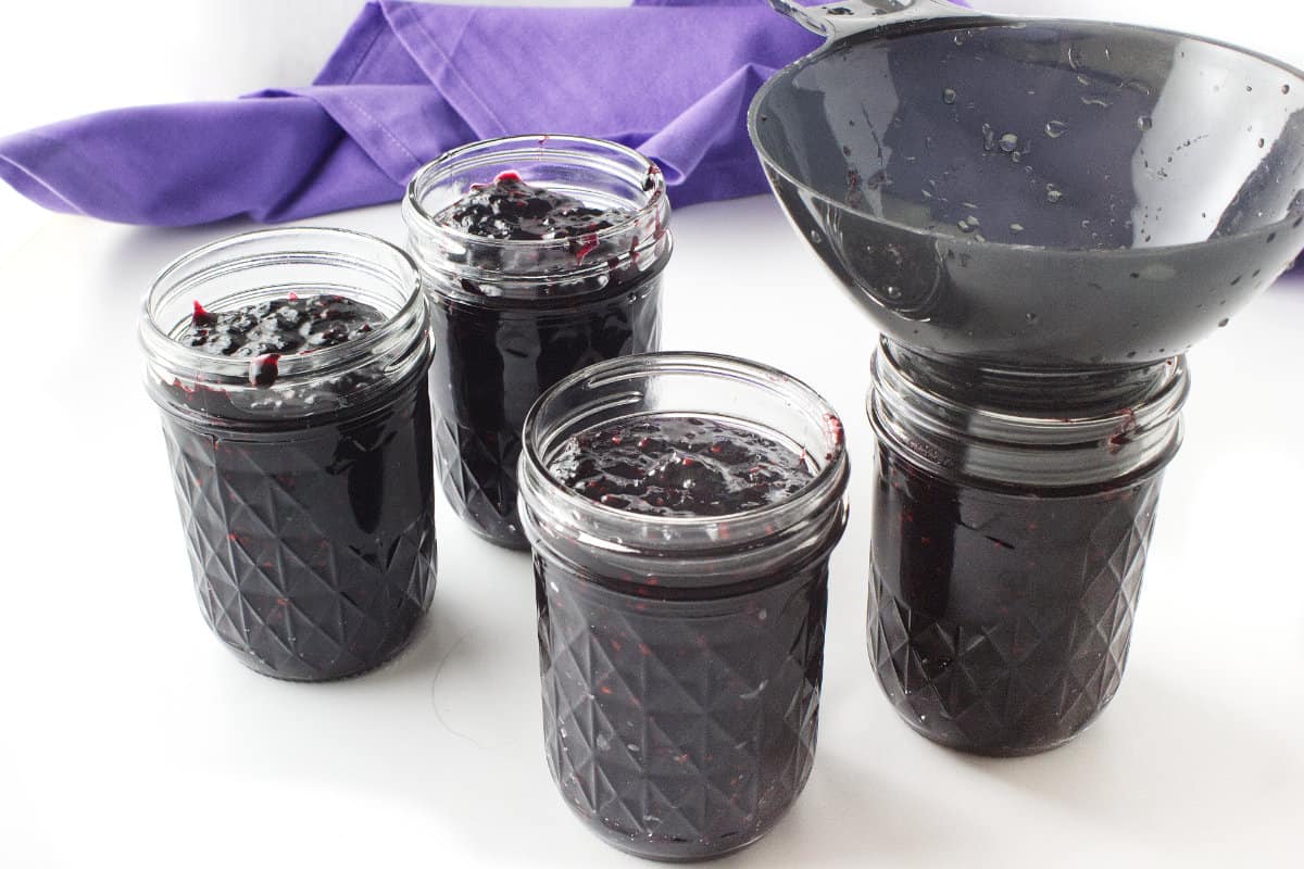 filling ball canning jars with blackberry jam.