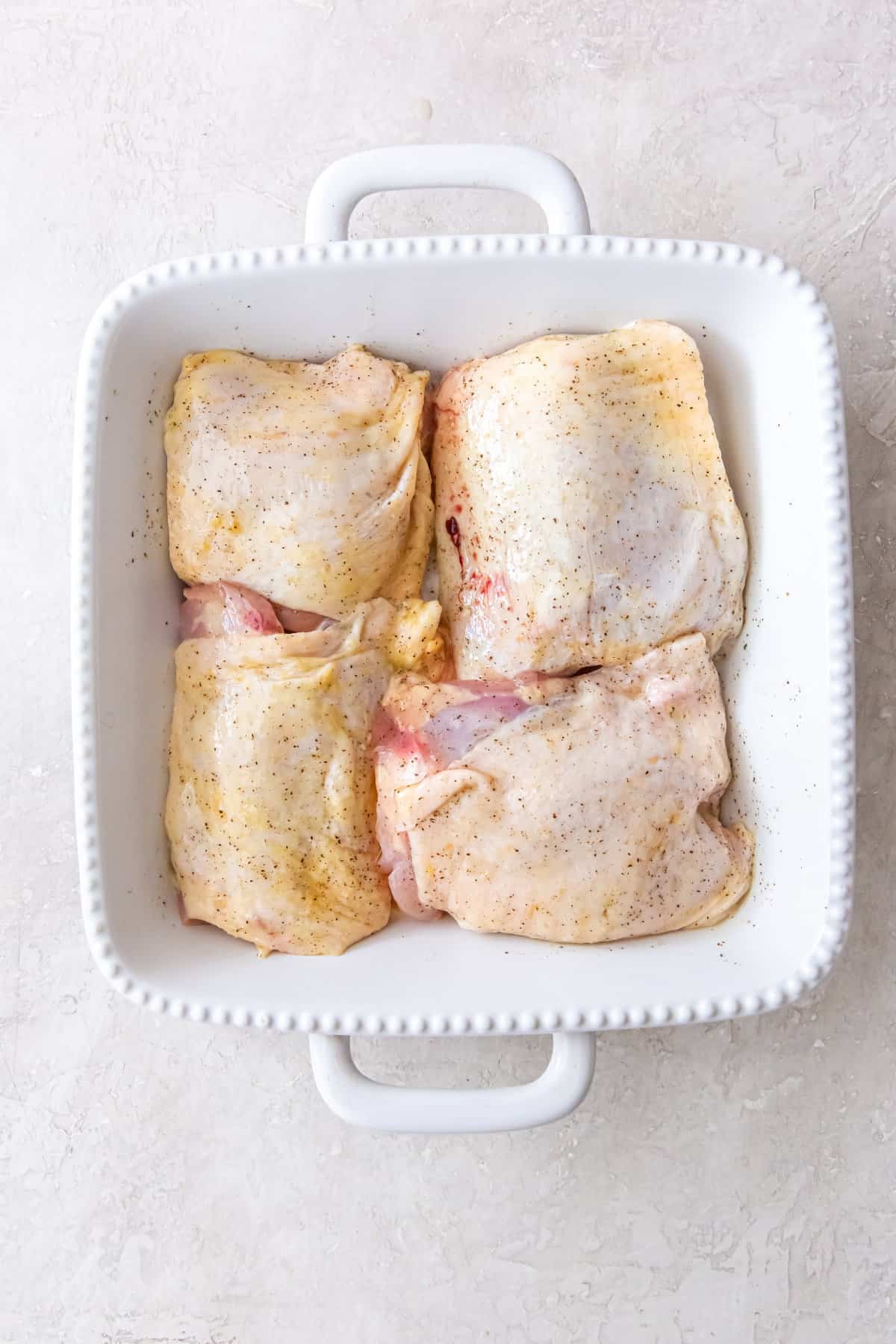 uncooked chicken thighs in a baking dish.