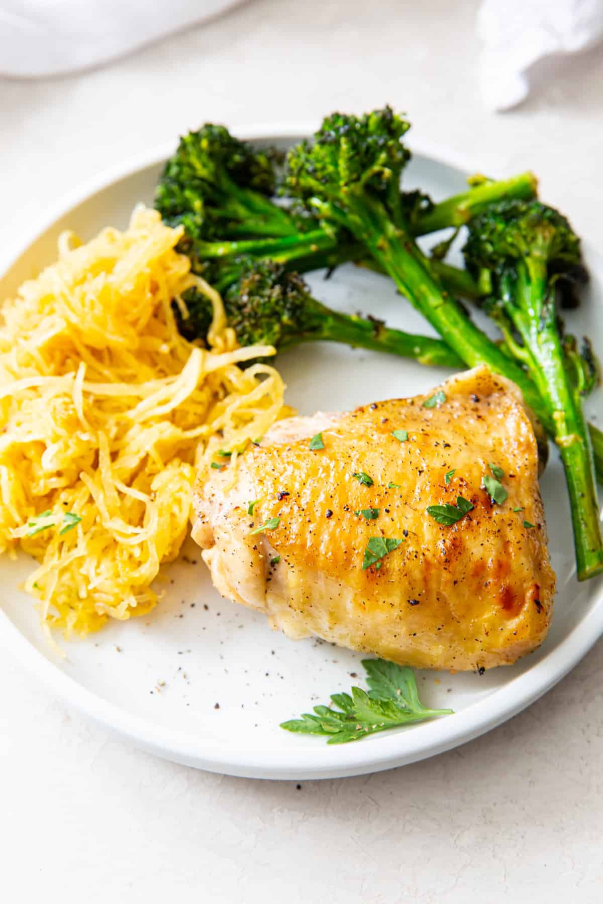 plate with broiled chicken thighs, broccolini, and spaghetti squash.
