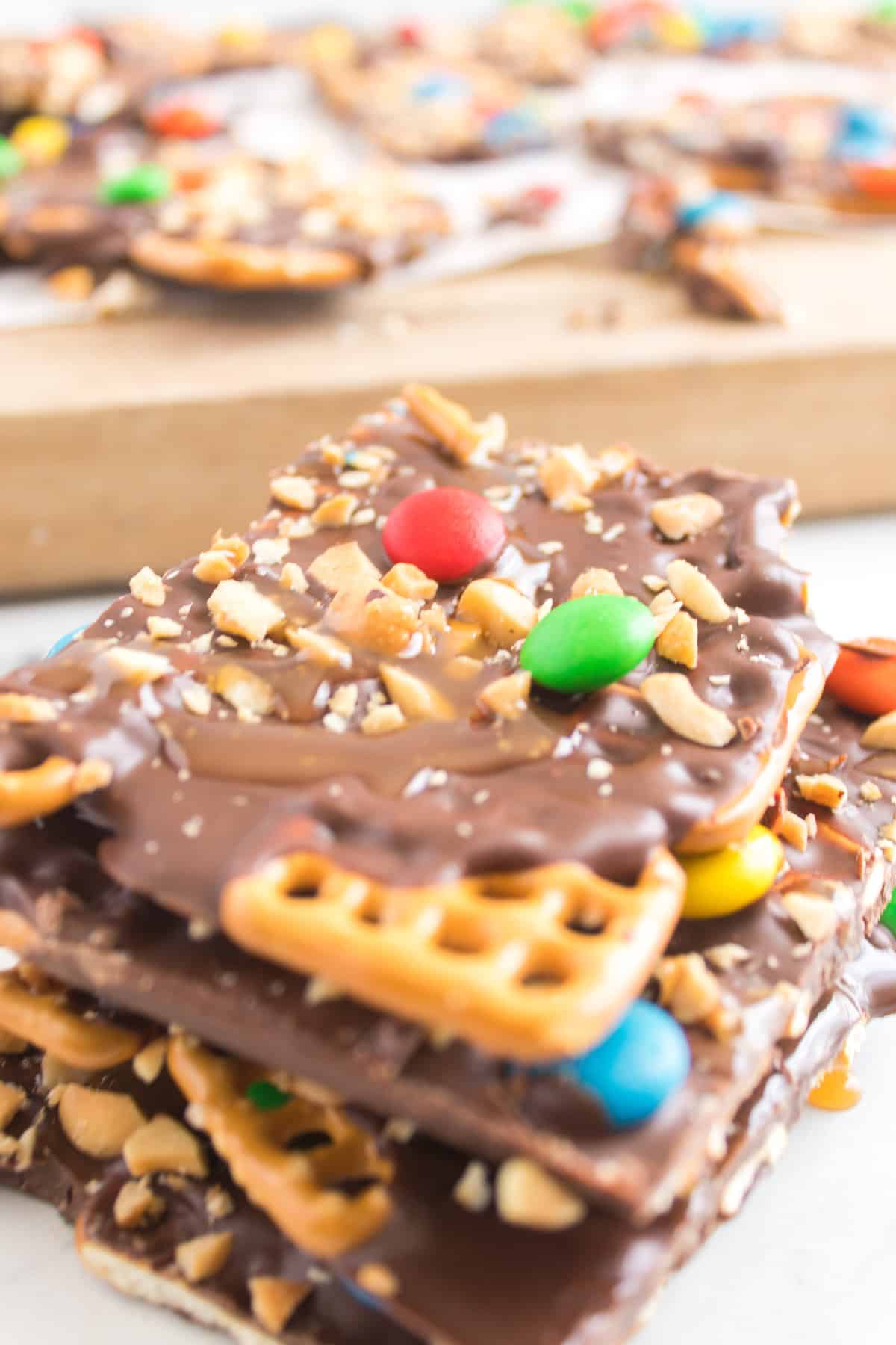 close up of chocolate drizzled pretzels with m and m's on it.