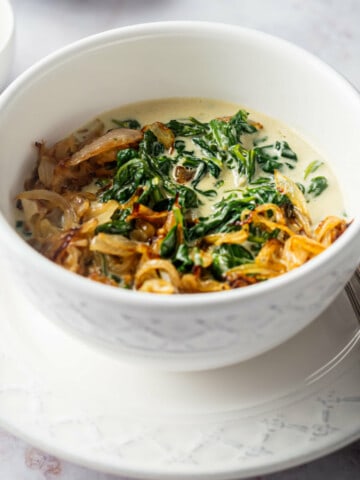 bowl of creamy spinach with fried onions on top.