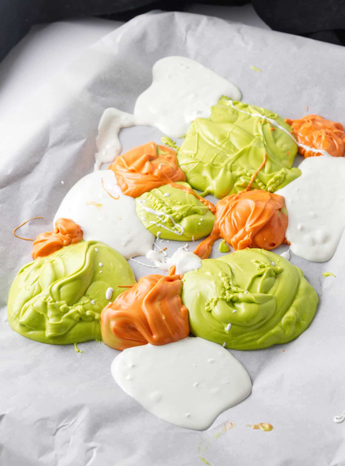 melted candy melts dolloped on a tray covered with parchment paper.