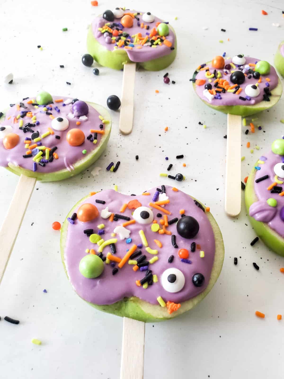 purple candy apple slices with halloween sprinkles.