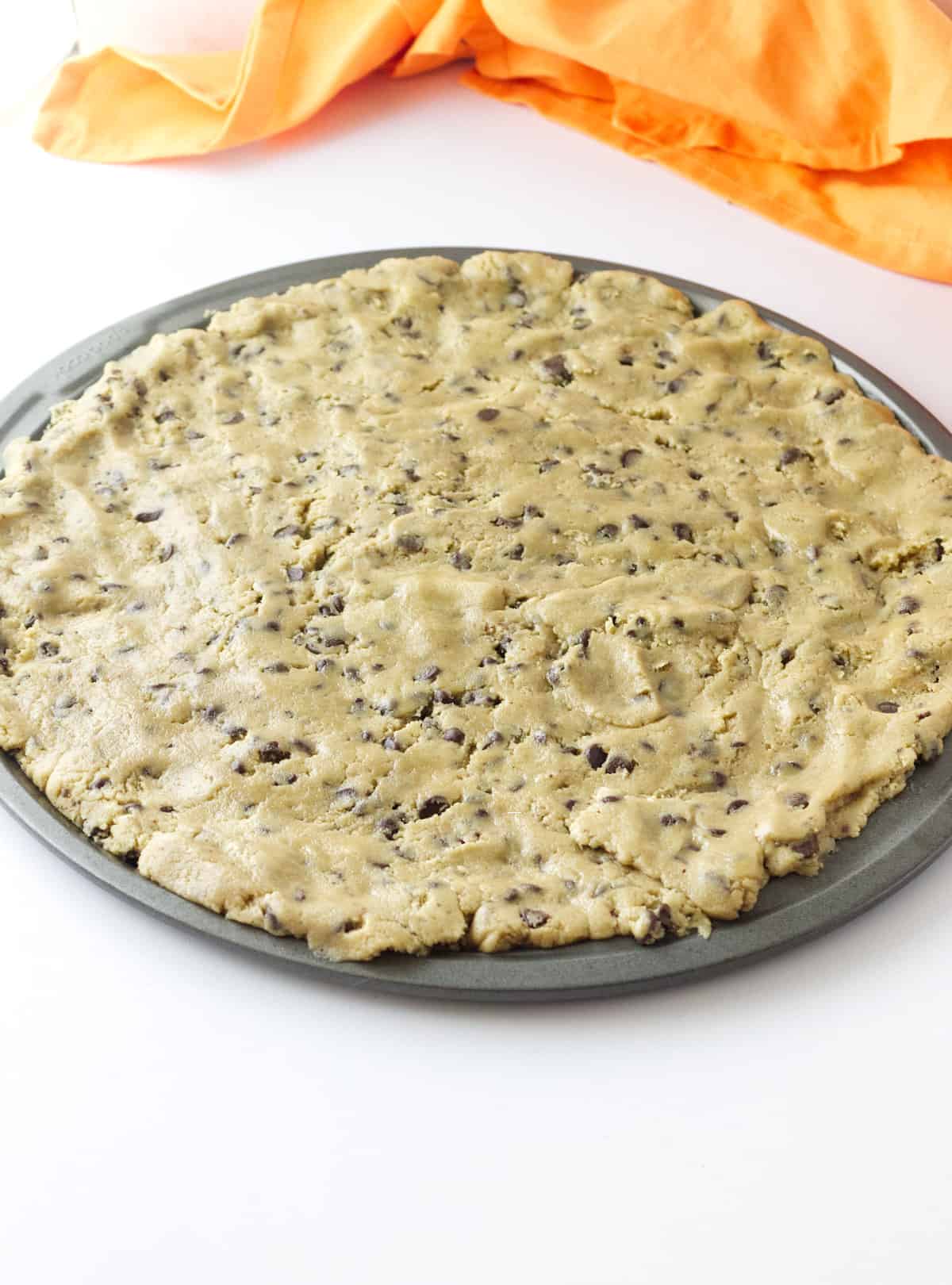 Pillsbury chocolate chip cookie dough pressed into a round pizza pan.