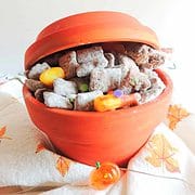 A orange bowl filled with halloween chex mix.