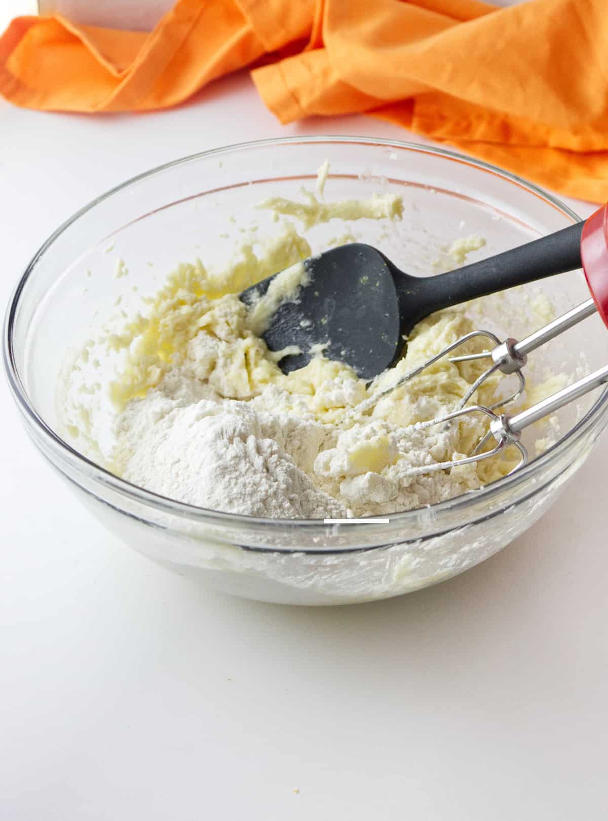 flour added to sugar and butter in a bowl.