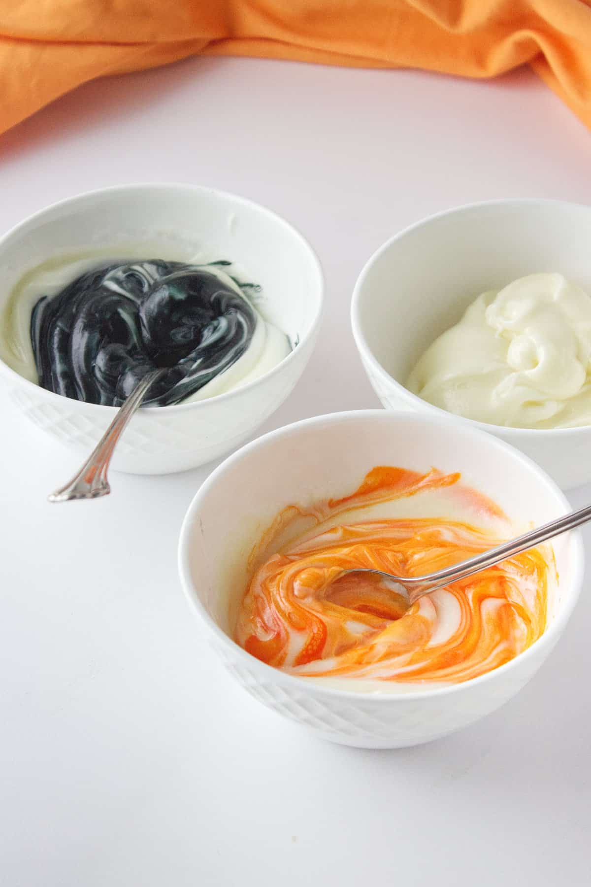 bowls of black, orange, and white frosting.