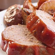 two slices of ketchup topped meatloaf with roasted potatoes.