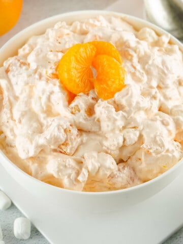bowl of whipped dessert with mandarin orange slice on top.
