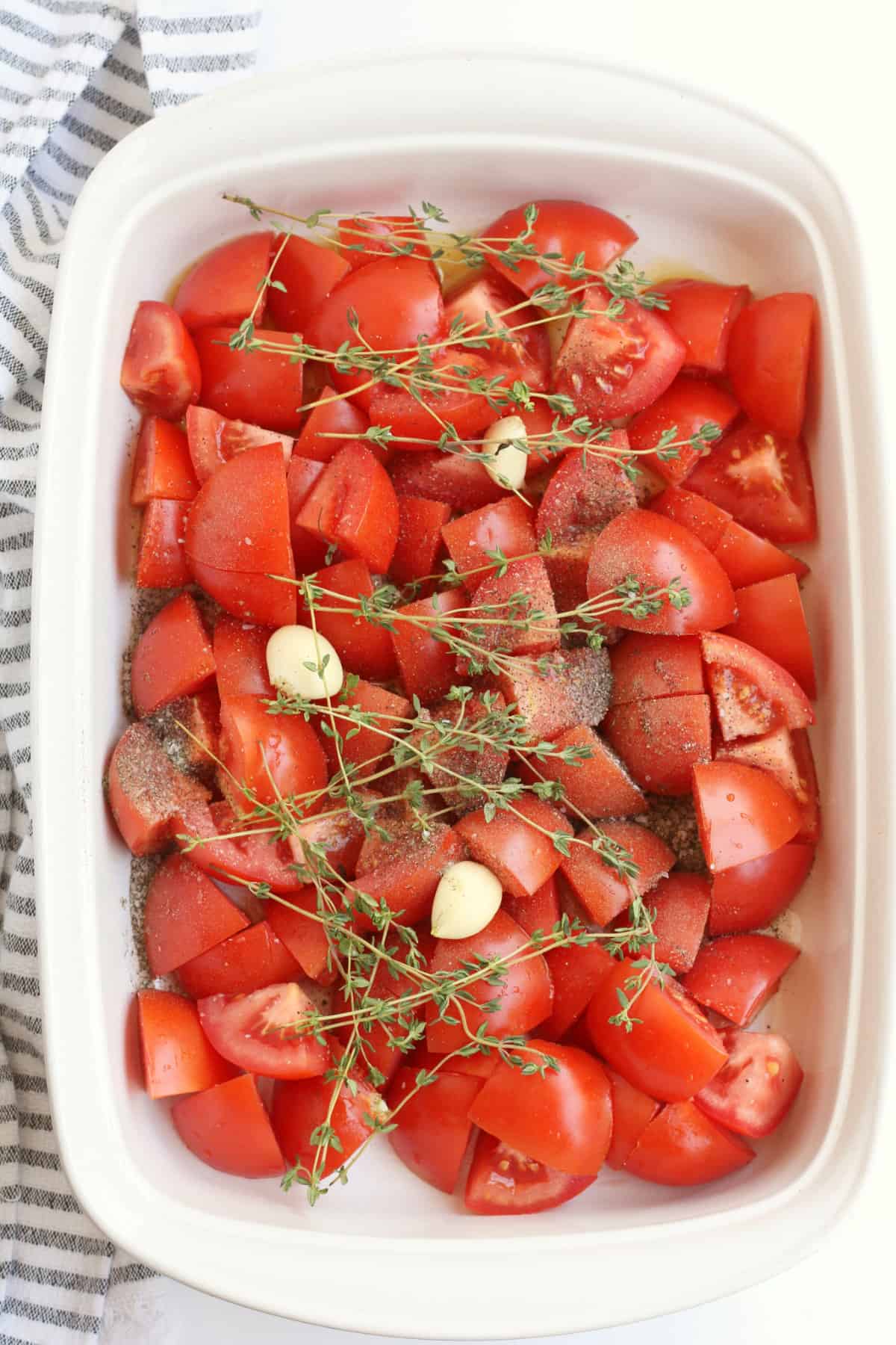 quartered tomatoes and herbs in a baking dish.
