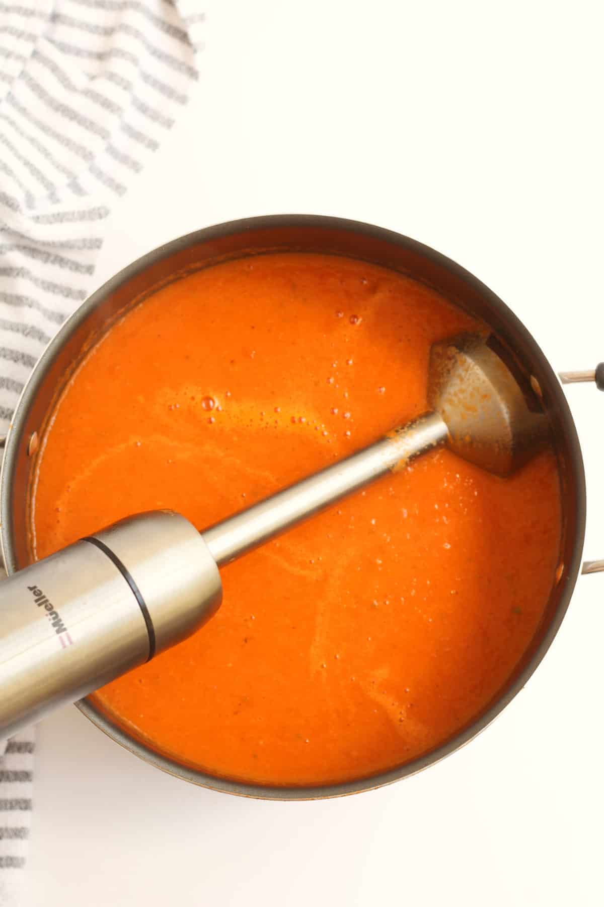stick blender in pot of tomato soup.