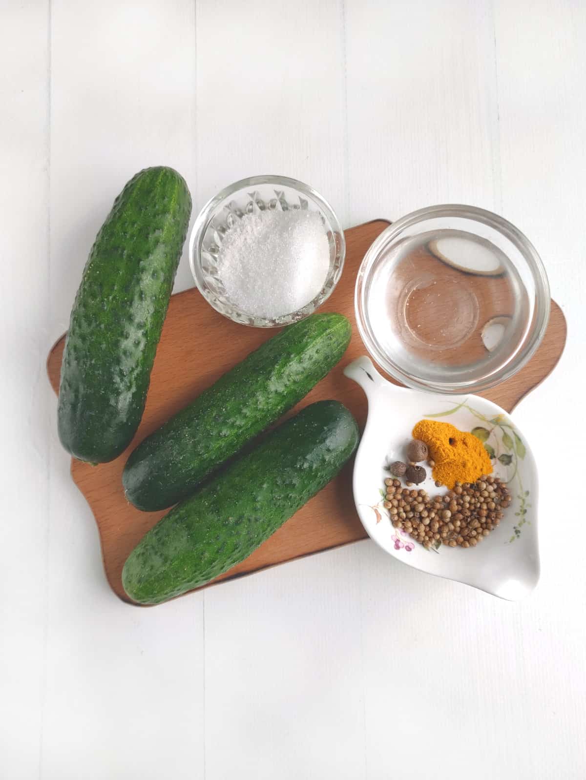 cucumbers, white vinegar, sugar, and bowl of pickling spices.