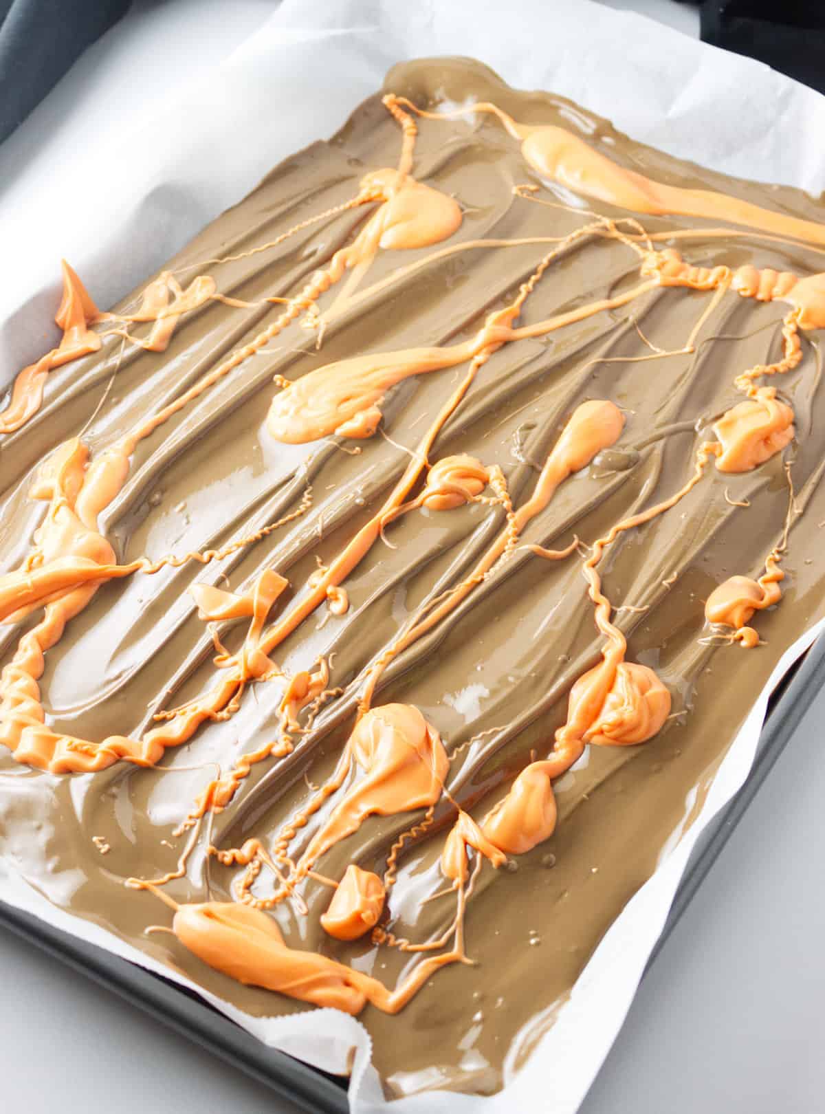 orange candy melts drizzled on a cookie sheet.