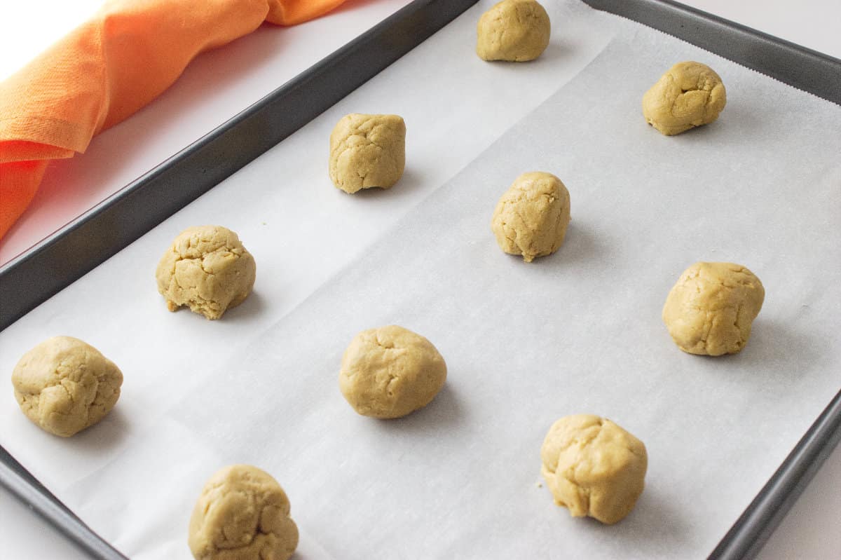 balls of peanut butter cookie dough on cookie sheet.