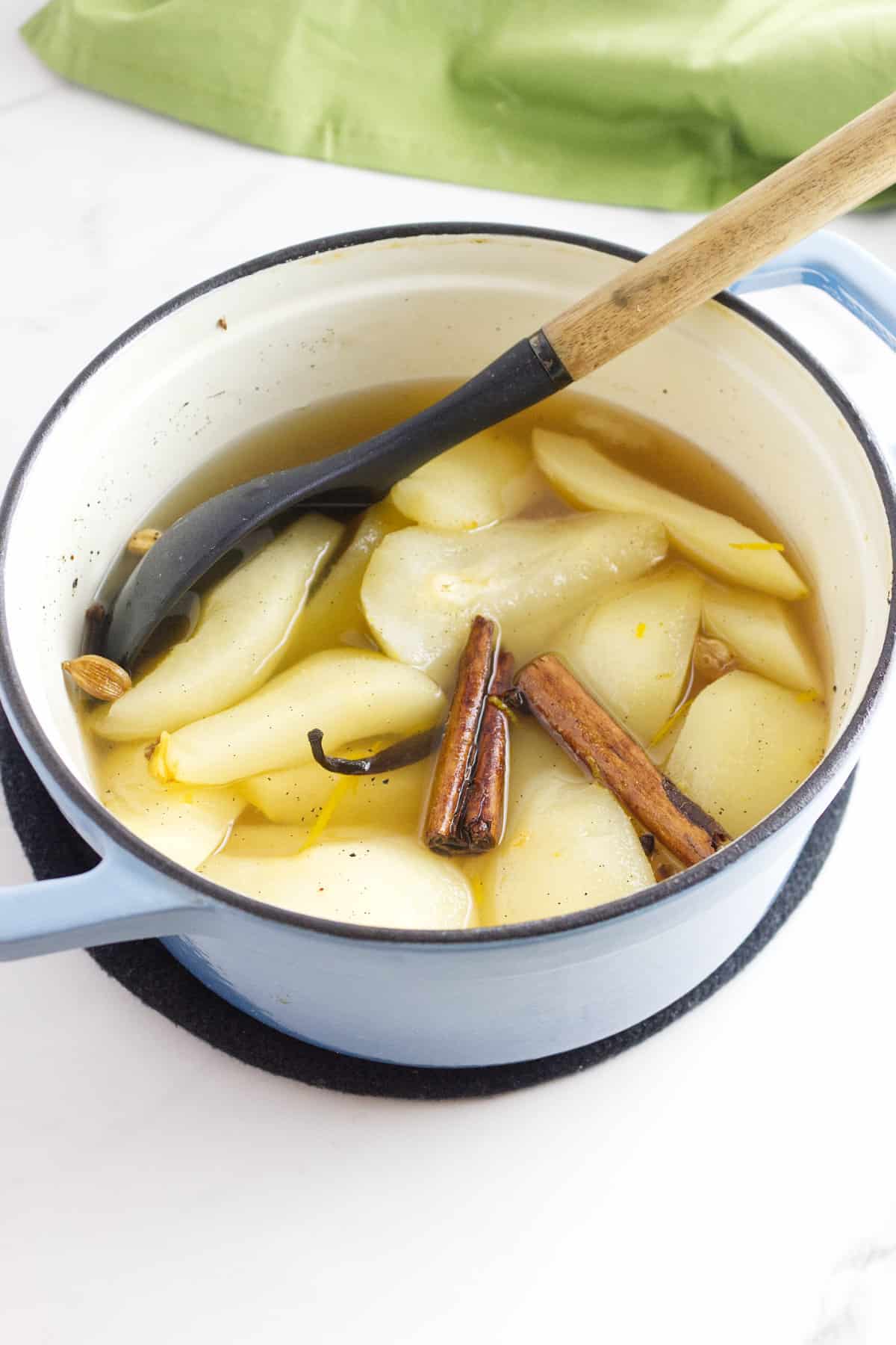 stewing quartered pears in a pot with spices.