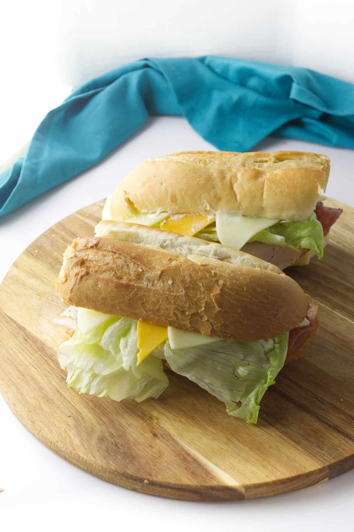 two hoagie sandwiches on a cutting board.